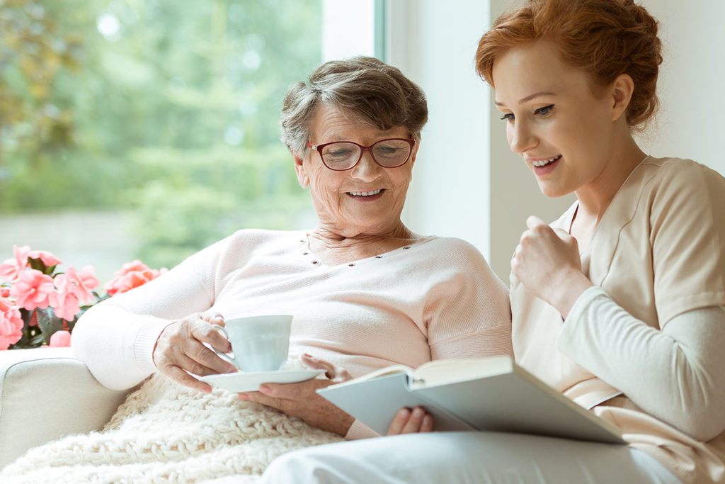 caretaker and patient reading in chair